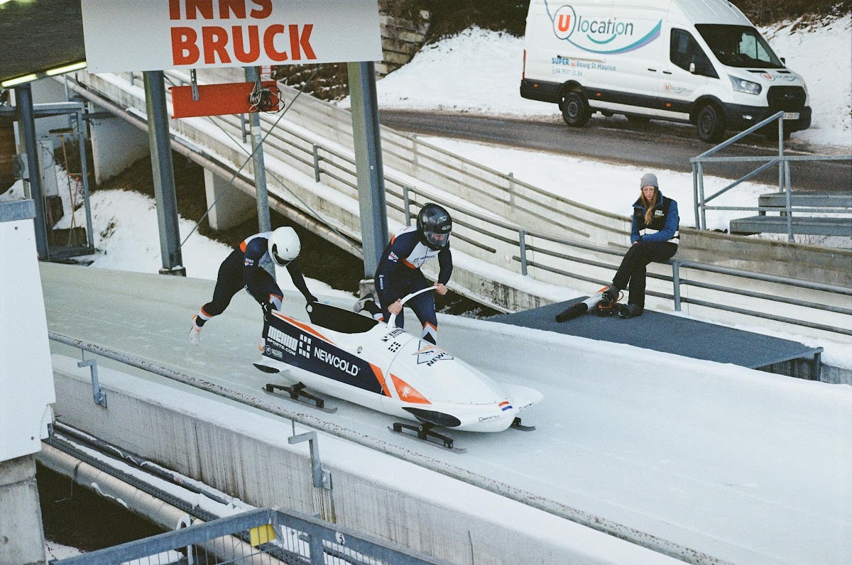 Team duwt de bobslee aan bij de start in Innsbruck